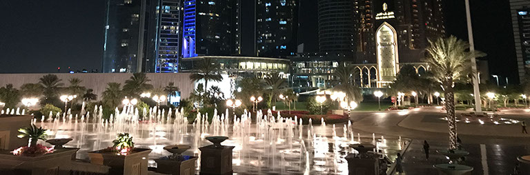 Nächtlicher Blick auf den beleuchteten Brunnen vor dem Emirates Palace Hotel und die Jumeirah at Etihad Towers in Abu Dhabi.